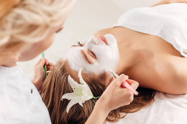 Lázeňské terapie pro mladé ženy obdrží obličejové masky v salonu krásy - doma — Stock fotografie
