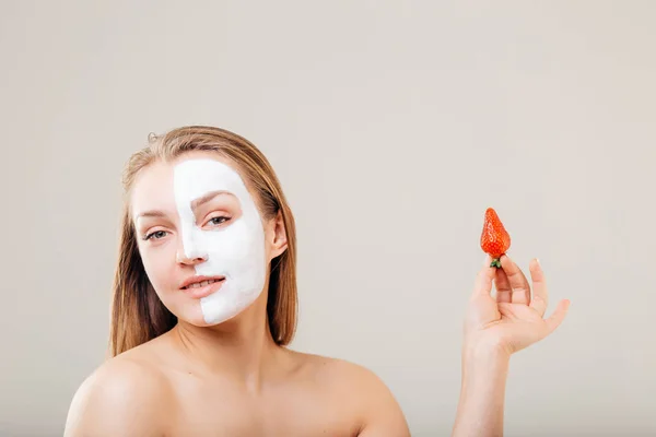 Wanita muda cantik dengan masker wajah dan strawberry, perawatan spa — Stok Foto