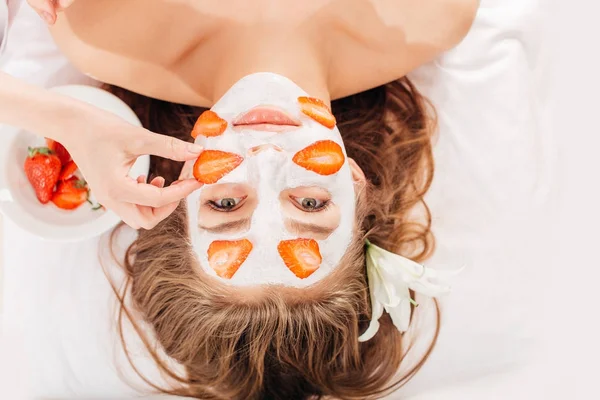 Wanita muda yang cantik menerima topeng buah di wajah di salon kecantikan - di dalam ruangan — Stok Foto