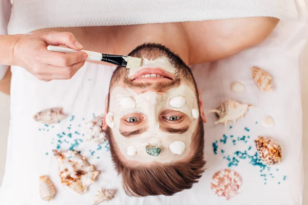 Retrato de hombre con máscara facial de arcilla en spa de belleza . — Foto de Stock