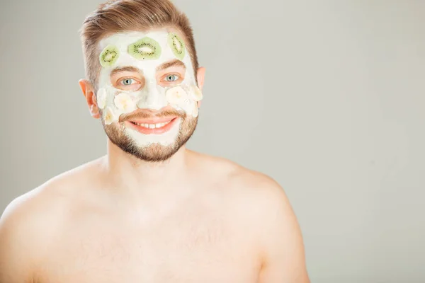 Homme avec masque cosmétique sur le visage, fond gris — Photo