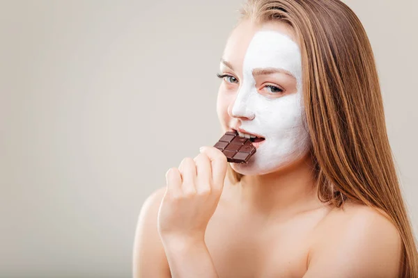 Portrait of beautiful woman with spa mask holding chocolate bar — Stok Foto