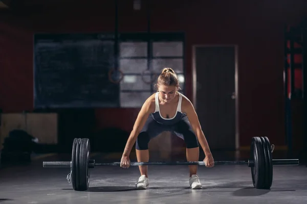 Vrouw met een barbell in haar handen. — Stockfoto