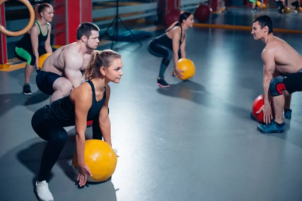 Squat sportowców z piłką w ręce. — Zdjęcie stockowe