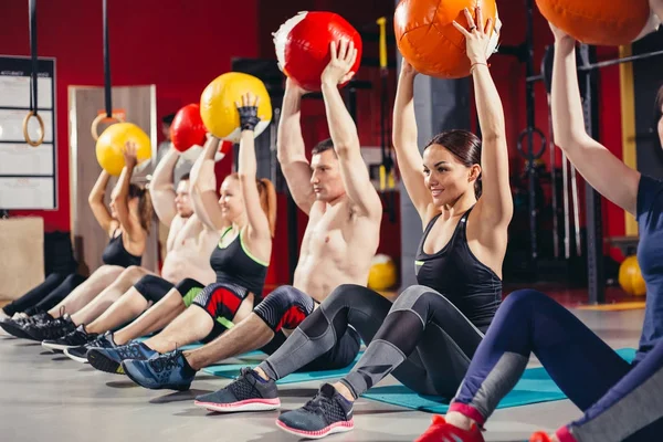 Homens e mulheres realizam a bola de exercício — Fotografia de Stock