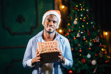 Noel hediyesi elinde tutan çekici gülümseme ile Afro Amerikan adam