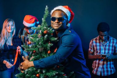 Afrika kökenli Amerikalı adam Noel ağacı ile sarılma