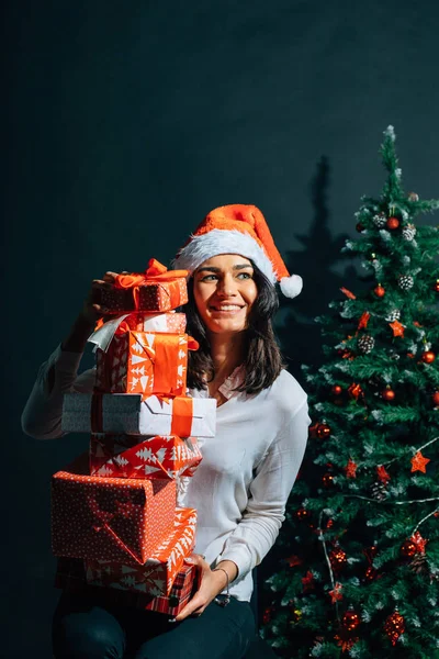 Flicka i santa hatt nära en julgran med gåvor — Stockfoto