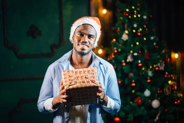 Noel hediyesi elinde tutan çekici gülümseme ile Afro Amerikan adam