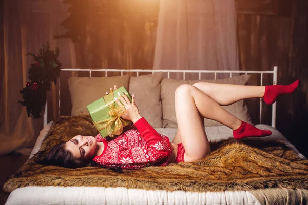 Sexig tjej i röda underkläder och tröja ligga nära julgran och öppna gåva — Stockfoto