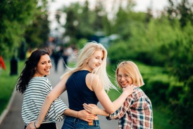 Çim ve hugs üzerinde oturan üç güzel kadın arkadan görünüm