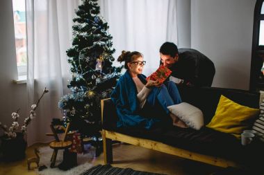 kadın açık hediye kutusu ve onun erkek arkadaşı ona yakın koltukta oturan süre gülümseyen