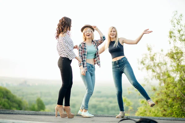 Three happy joyful young women jumping and laughing together at park — Stock Photo, Image