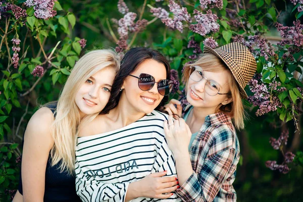 Três mulheres casuais confiantes em pé no parque e olhando para a câmera — Fotografia de Stock