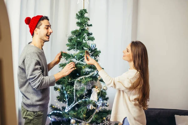 Linda pareja joven decorando un árbol de Navidad — Foto de Stock