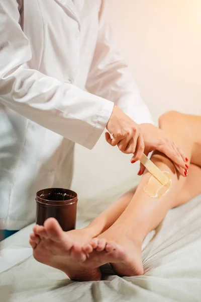 Detailní záběr kosmetička voskování ženské nohy v lázeňském centru — Stock fotografie