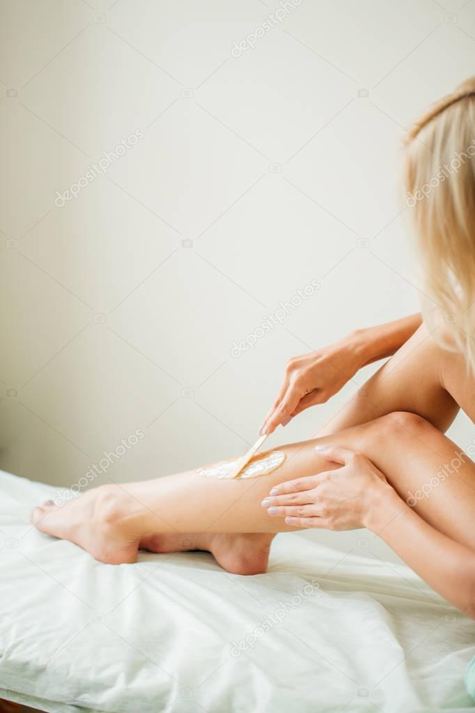 Young woman waxing her lower leg with honey