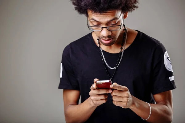 Zwarte man in trendy op zoek via pcitures via sociale media, met behulp van mobiele telefoon — Stockfoto