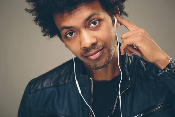 Hombre africano feliz sonriendo escuchando música en auriculares. Fondo blanco . — Foto de Stock