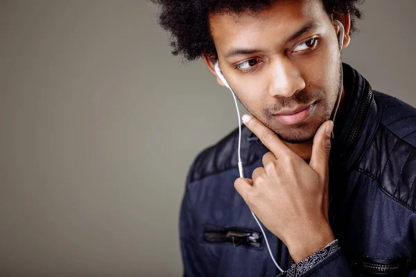 Hombre africano feliz sonriendo escuchando música en auriculares. Fondo blanco . — Foto de Stock