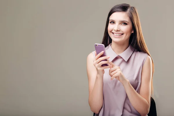 Porträt einer lächelnden, lässigen Frau mit Smartphone vor weißem Hintergrund — Stockfoto