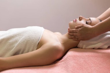 Kapalı gözlü bir kadın kaplıcada yüz veya kafa masajı yaptırıyor.