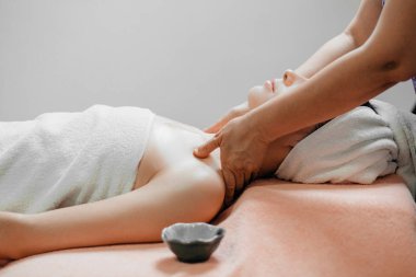 Kapalı gözlü bir kadın kaplıcada yüz veya kafa masajı yaptırıyor.