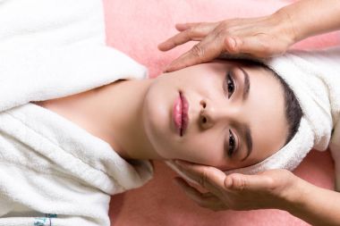 Kapalı gözlü bir kadın kaplıcada yüz veya kafa masajı yaptırıyor.