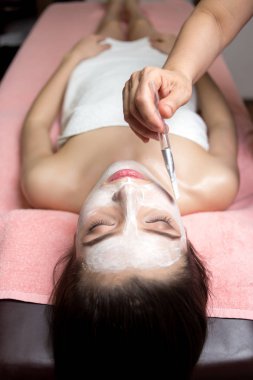 Kadın yalan söylüyor ve kozmetik uzmanı kaplıcada yüz maskesi takıyor.