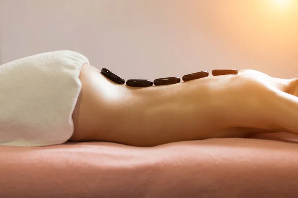 Spa Stone Massage. Hermosa mujer consiguiendo spa piedras calientes masaje en el salón de spa. — Foto de Stock