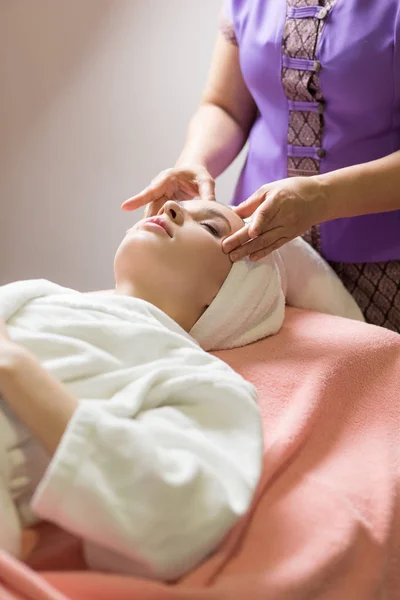 Woman lying with closed eyes and having face or head massage in spa — Stock Photo, Image