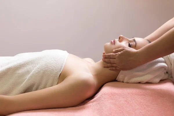 Woman lying with closed eyes and having face or head massage in spa — Stock Photo, Image