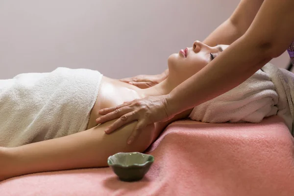 Mujer acostada con los ojos cerrados y masajeando cara o cabeza en el spa — Foto de Stock