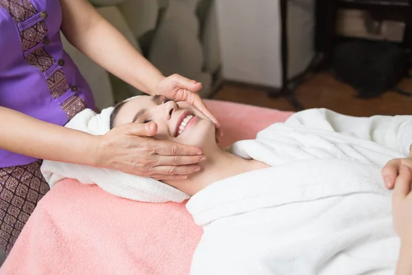 Woman lying with closed eyes and having face or head massage in spa — Stock Photo, Image