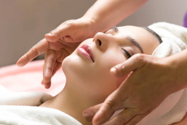 Woman lying with closed eyes and having face or head massage in spa — Stock Photo, Image