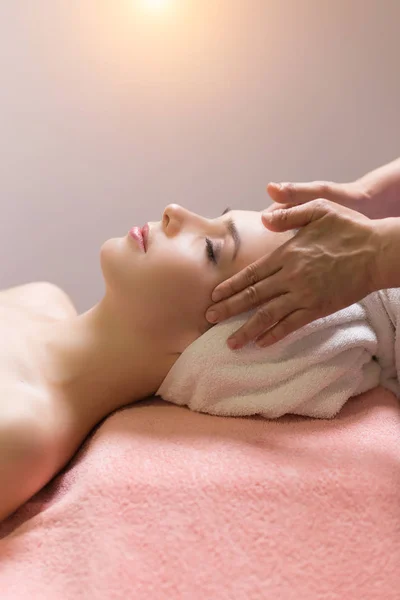 Woman lying with closed eyes and having face or head massage in spa — Stock Photo, Image