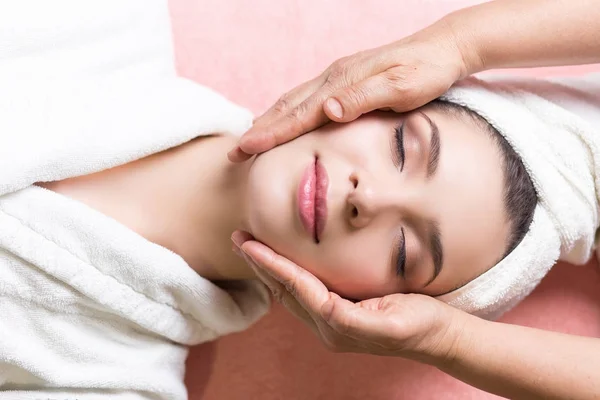 Mujer acostada con los ojos cerrados y masajeando cara o cabeza en el spa — Foto de Stock