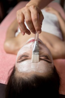 Kadın yalan söylüyor ve kozmetik uzmanı kaplıcada yüz maskesi takıyor.