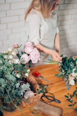 pretty young woman making fashion modern bouquet of different flowers.