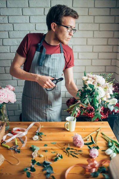 Floristería masculina joven que trabaja en el mostrador en la tienda de flores — Foto de Stock