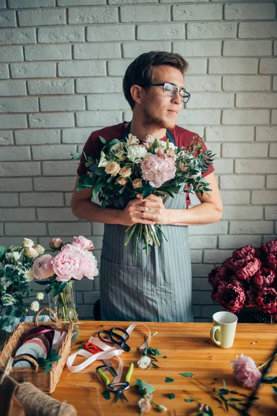 Linda florista masculina joven concentrada en gafas que trabajan en la tienda de flores — Foto de Stock