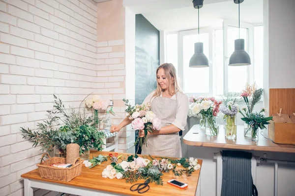 Local de trabalho florista: mulher organizando um buquê com flores — Fotografia de Stock