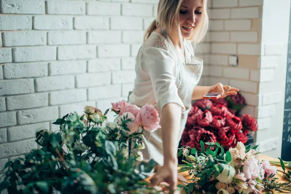 Florist arbetsplats: kvinna arrangerar en bukett med blommor — Stockfoto