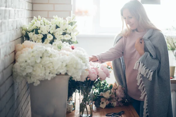 Sorrindo linda florista jovem arranjando plantas na loja de flores — Fotografia de Stock
