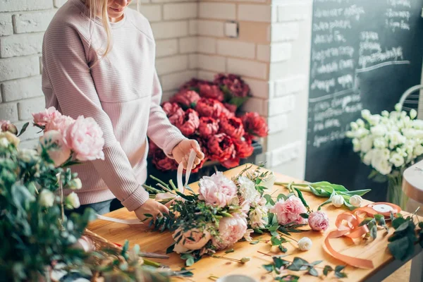 Manos de florista contra escritorio con herramientas de trabajo y cintas — Foto de Stock