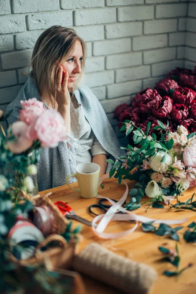 Jovem florista do sexo feminino falando no telefone e fazendo anotações na loja de flores . — Fotografia de Stock