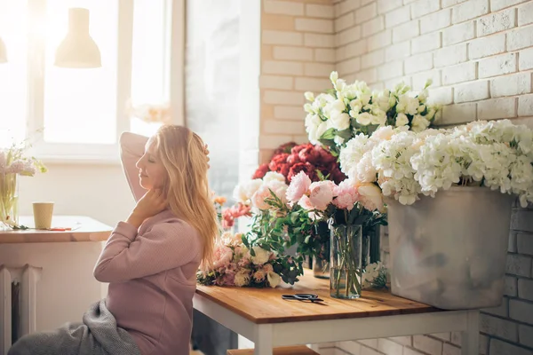 Feliz bela florista jovem em óculos sentados na loja de flores — Fotografia de Stock
