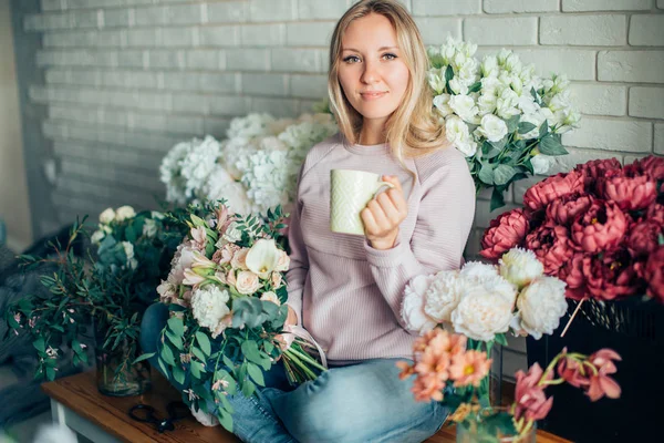 Porträt einer jungen Floristin mit roten Tulpen, die in die Kamera blickt — Stockfoto