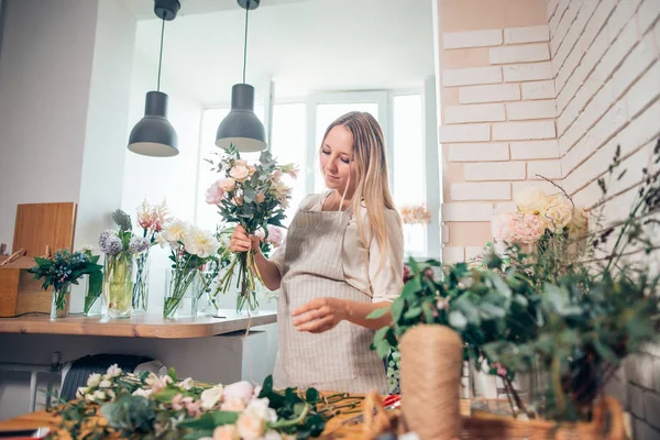 Floristería en el trabajo: bonita joven rubia haciendo ramo de flores diferentes — Foto de Stock