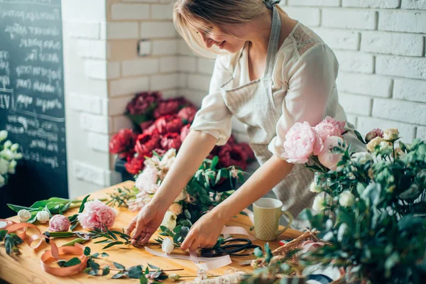 Sorrindo linda florista jovem arranjando plantas na loja de flores — Fotografia de Stock